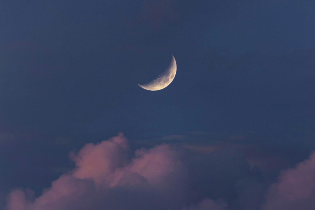 Eine Sichel des Mondes ist am Abendhimmel über einer Wolke zu sehen. Eine Sichel des Mondes ist am Abendhimmel über einer Wolke zu sehen.