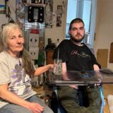 Petra und Peer Bangel sitzen nebeneinander auf der Couch in ihrem Wohnzimmer.