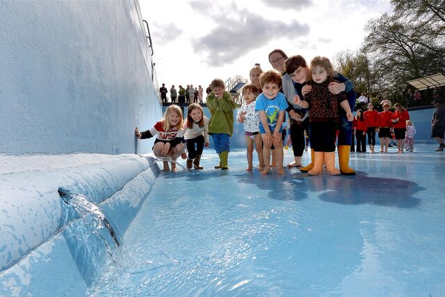 Kinder und Erwachsene stehen im Schwimmerbecken des Freibads Dellwig. Im Vordergrund läuft Wasser ins Becken.