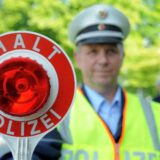 Ein Polizeibeamter der Kreispolizeibehörde Unna hält ein „Halt Polizei“-Schild hoch.