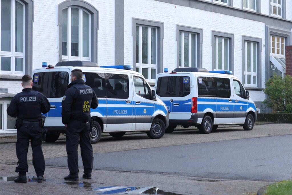 Polizeibeamte stehen in der Nähe eines Gebäudes, das durchsucht wird. Polizeibeamte stehen in der Nähe eines Gebäudes, das durchsucht wird.