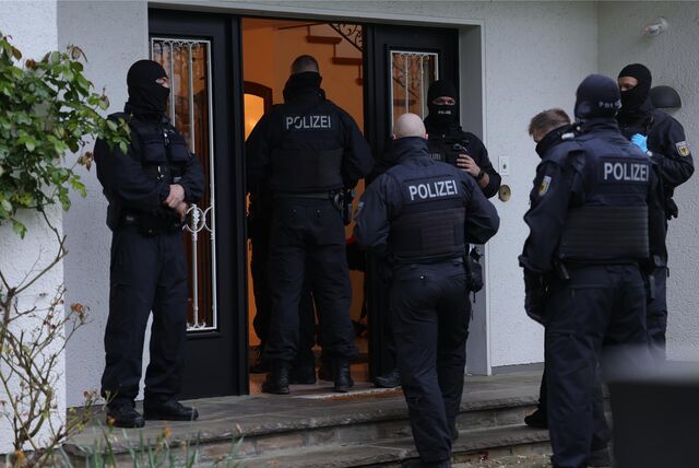 Polizisten sind bei einer Razzia im Einsatz und betreten ein Mehrfamilienhaus.