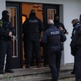 Polizisten sind bei einer Razzia im Einsatz und betreten ein Mehrfamilienhaus.