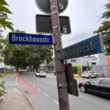 Die Straßenschilder von Brockhausstraße und Hertingerstraße stehen im Vordergrund der betreffenden Einmündung.