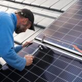 Ein Handwerker bringt eine Photovoltaikanlage auf einem Dach an.
