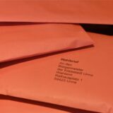 Mehrere rote Wahlbriefe an den Bürgermeister der Kreisstadt Unna liegen auf einem Haufen