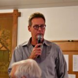 Oliver Grewe hält ein Mikrofon.