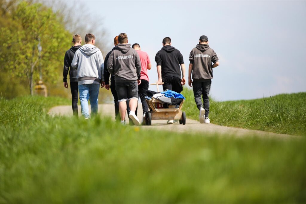 Jugendliche machen am 1. Mai eine Wanderung mit einem Bollerwagen.