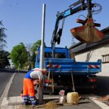 Ein Bauarbeiter arbeitet an einem neuen Ampelmast. Daneben steht ein Lastwagen mit einem Baggerarm