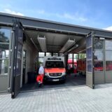 Durch das offene Tor der Rettungswache Unna-Nord in Alte Heide sind ein Rettungswagen und ein Mitarbeiter des Rettungsdienstes zu sehen.