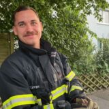 Zufrieden mit seinem Einsatz: Dieser Feuerwehrmann hält strahlend das gerettete Küken in den Händen.