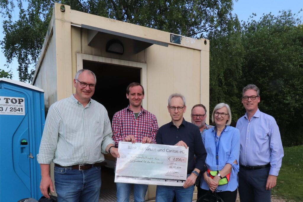 (V. l. n. r.) Ralf Plogmann (Vorstand Caritasverband), René Pohle (Hausmeister der Übernachtungsstelle), Guido Ponto (Vorsitzender Katharinenstiftung), Ludger Büngener (Kuratorium Katharinenstiftung), Regina Müller und Michael Löblein (beide Vorstand Katharinenstiftung) stehen vor dem Container.