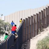 Migranten klettern über einen Zaun auf der italienischen Insel Lampedusa.