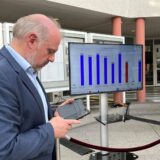 Bürgermeister Dirk Wigant steht während einer Wahlveranstaltung in der Bürgerhalle des Unnaer Rathauses. Er schaut auf ein Handy.