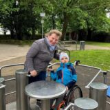 Mael sitzt das erste Mal mitsamt seines Rollstuhls im inklusiven Karussell auf dem Burgspielplatz.