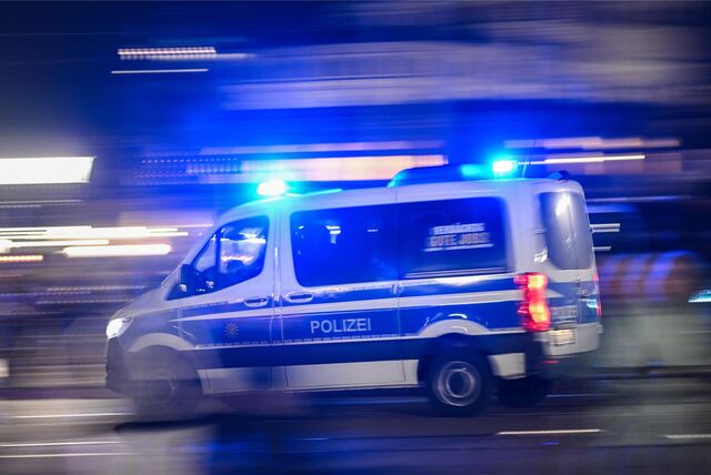 Ein Polizeiauto fährt mit Blaulicht am Rande einer Demonstration