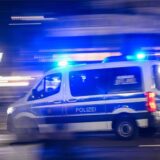 Ein Polizeiauto fährt mit Blaulicht am Rande einer Demonstration