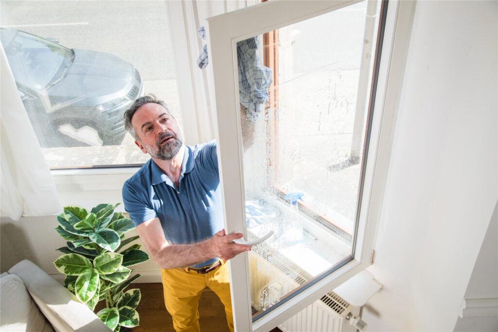 Ein Mann putzt die Fenster seiner Wohnung. An viel befahrenen Straßen sind die Fensterscheiben schneller verschmutzt. Ein Mann putzt die Fenster seiner Wohnung. An viel befahrenen Straßen sind die Fensterscheiben schneller verschmutzt.