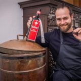 Felix Krämer zeigt hier zwei Produkte des Familienunternehmens in Dortmund: den Kräuterlikör und eine Praline.