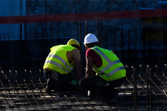 Zwei Männer sitzen auf einer Baustelle eines Wohnhauses.