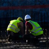 Zwei Männer sitzen auf einer Baustelle eines Wohnhauses.