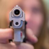 Der Lauf einer Schusswaffe zielt direkt in die Kamera.