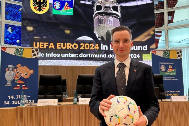 Der städtische EURO-Beauftragte Martin Sauer mit einem Fußball in den Händen und Plakaten zur Fußball-EM im Dortmunder Rathaus.