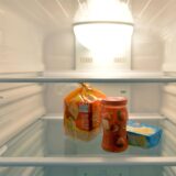 Ein Toastbrot, ein Glas Marmelade und ein Stück Butter liegen in einem Kühlschrank