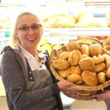 Zwei Bäckereifachverkäuferinnen halten einen Korb mit Brötchen in die Kamera.