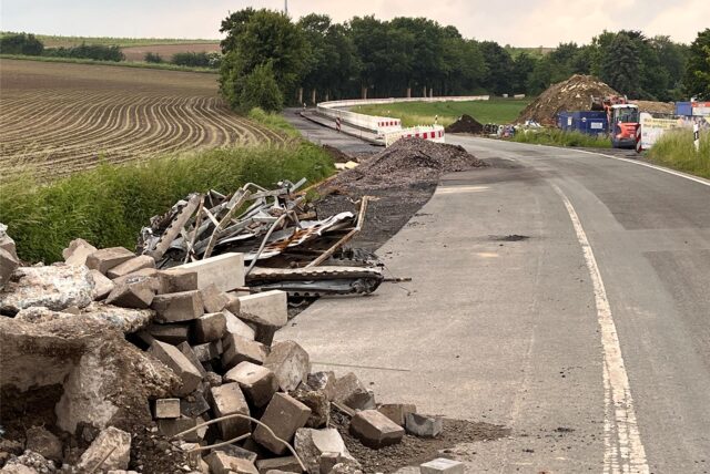 Am Rand der Türkenstraße zwischen Unna und Billmerich lagert Bauschutt. Im Hintergrund sind Baumaschinen und Absperrungen