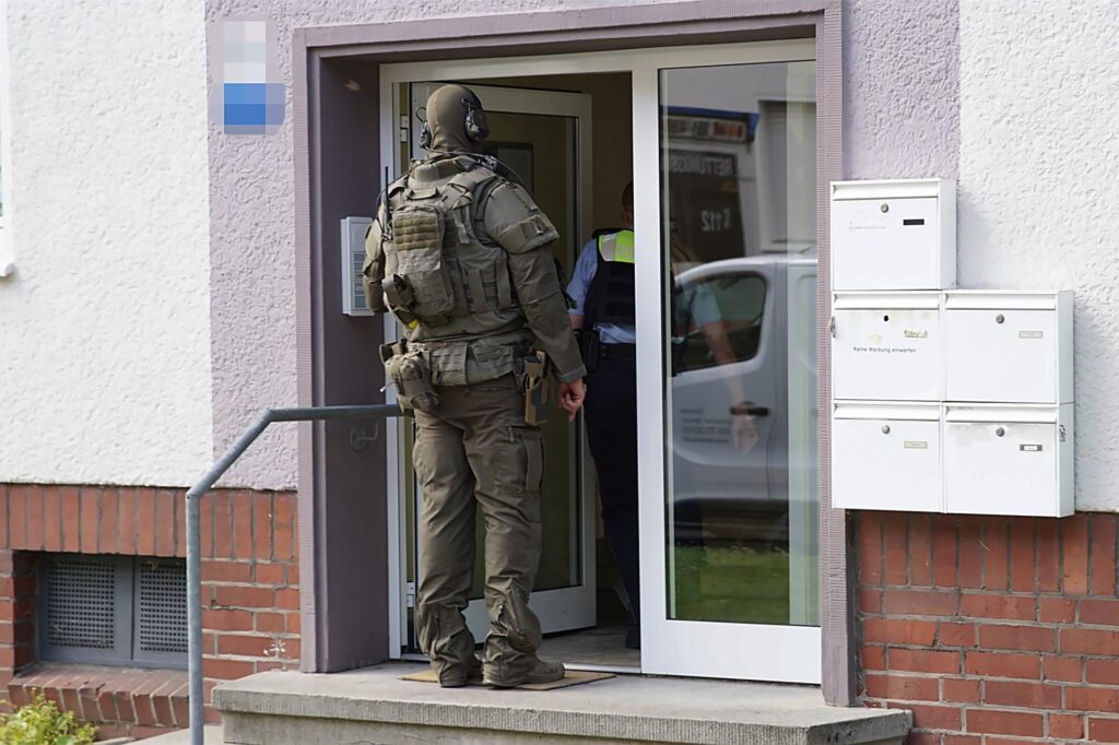 Ein Polizist und ein SEK-Beamter gehen in das Wohngebäude, in dem sie einen Mann dazu bewegen sollten, einen Termin im Amtsgericht wahrzunehmen. 