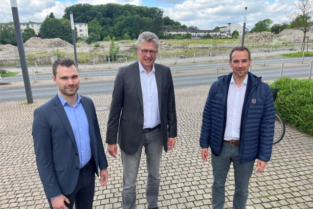 Wirtschaftsförderer Marvin Faulstich, Bergkamens Bürgermeister Bernd Schäfer und Sven Klagge, Leiter der Ten-Brinke-Niederlassung Münster, stehen vor der Turmarkaden-Brache an der Töddinghauser Straße in Bergkamen.