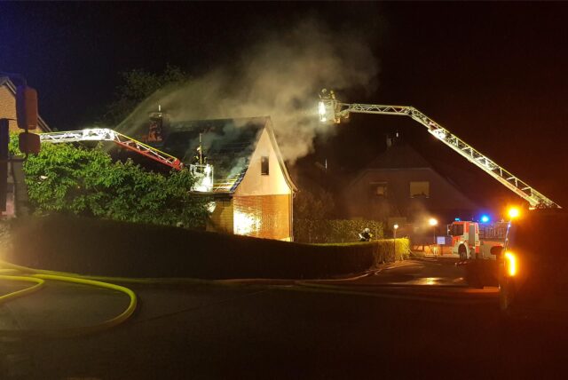 Ein Haus mit Rauch und Feuerwehrdrehleitern