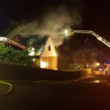 Ein Haus mit Rauch und Feuerwehrdrehleitern