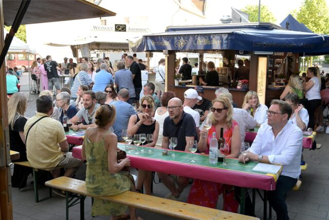 Gäste sitzen beim Weinfest in Lünen am Stand eines Winzers.
