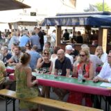 Gäste sitzen beim Weinfest in Lünen am Stand eines Winzers.
