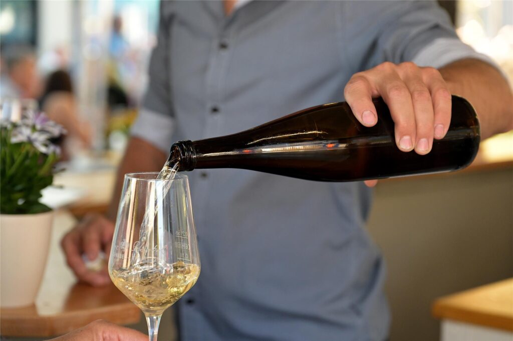 Ein Winzer gießt beim Weinfest in Lünen Weißwein in ein Glas. Ein Winzer gießt beim Weinfest in Lünen Weißwein in ein Glas.