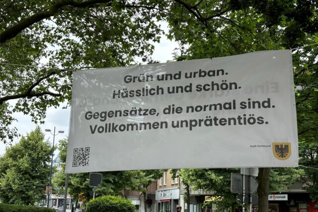 Im Stadtgarten in der Innenstadt von Dortmund hängt ein Banner, das Werbung macht für die Stadt.