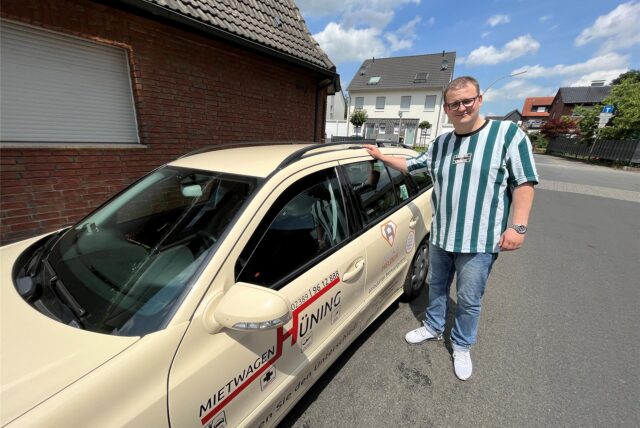 Ein Mann steht neben einem Auto.