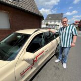 Ein Mann steht neben einem Auto.