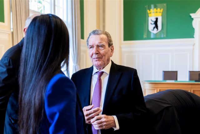 Altkanzler Gerhard Schröder (SPD, r-l), sein Rechtsanwalt Michael Nagel (verdeckt) und seine Ehefrau Soyeon Schröder-Kim (von hinten) unterhalten sich im Oberverwaltungsgericht (OVG) Berlin-Brandenburg nach der mündlichen Verhandlung im Prozess um den Verlust seines Büros im Bundestag.