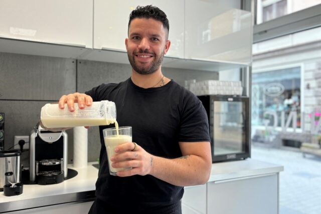 Ein Mann schüttet einen Eiweißdrink aus einem Shaker in ein Glas.
