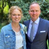 Lena und Tim Wolter stehen nach ihrer standesamtlichen Trauung dicht nebeneinander und lächeln freundlich in die Kamera.