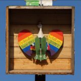 Der hölzerne Vogel hängt in Regenbogenfarben zum Abschuss bereit.