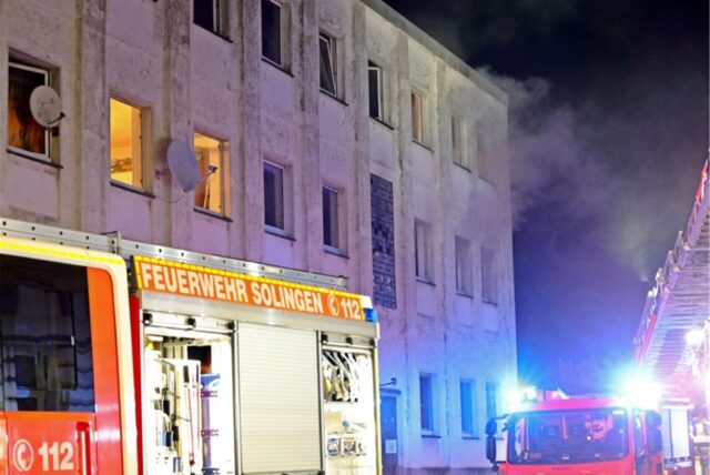 Rauch kommt aus den Fenstern eines Mehrfamilienhauses.