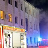 Rauch kommt aus den Fenstern eines Mehrfamilienhauses.