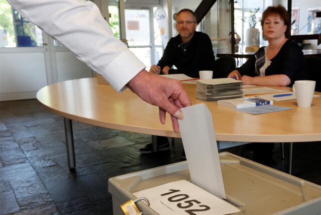 Ein Mann schmeißt seinen Stimmzettel in die Urne eines Wahllokals im Kreis Unna.