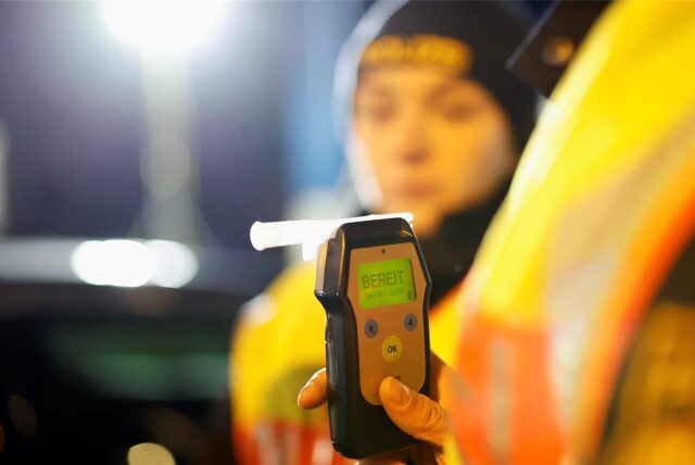 Eine Polizistin misst den Atemalkoholgehalt eines Autofahrers mit einem Alkoholtester, um festzustellen, ob er möglicherweise unter Alkoholeinfluss steht.
