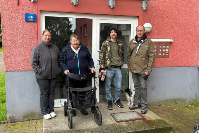 Drei Bewohner und eine Besucherin posieren vor dem Hauseingang.