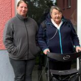 Drei Bewohner und eine Besucherin posieren vor dem Hauseingang.